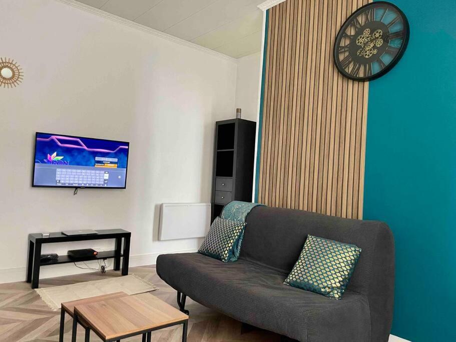 ein Wohnzimmer mit einem Sofa und einer Uhr an der Wand in der Unterkunft Appartement accueillant aux portes de Paris in Bobigny