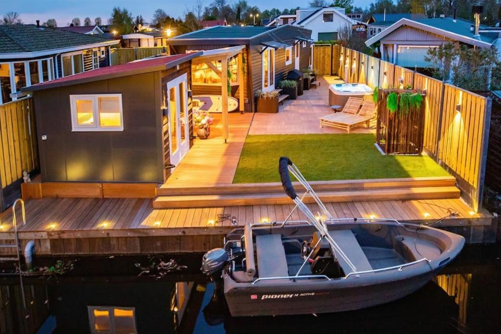 ein winziges Haus auf einem Dock mit einem Boot auf dem Wasser in der Unterkunft Cabana incl boat, jacuzzi,subboarts on a quiet park with private parking in Loosdrecht