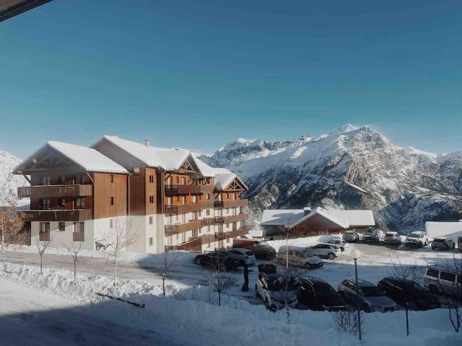 un bâtiment dans la neige avec des montagnes en arrière-plan dans l'établissement Appartement Puy Saint Vincent 1800, à Puy-Saint-Vincent