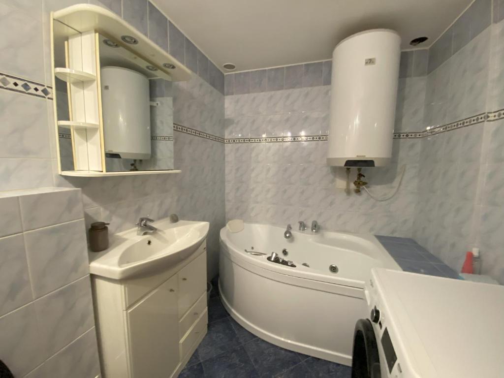 La salle de bains est pourvue d'un lavabo, d'une baignoire et de toilettes. dans l'établissement Cozy Downtown Garden Apartment: Spacious, Historical & Culinary Delight!, à Prague