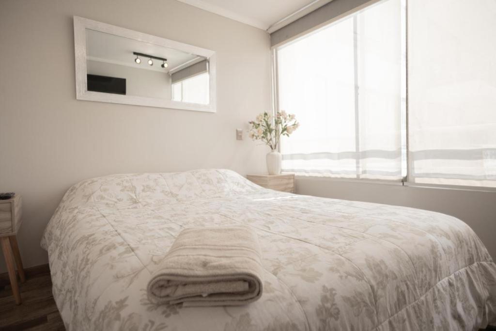 um quarto branco com uma cama com toalhas em PRO HOME NOVO em Antofagasta