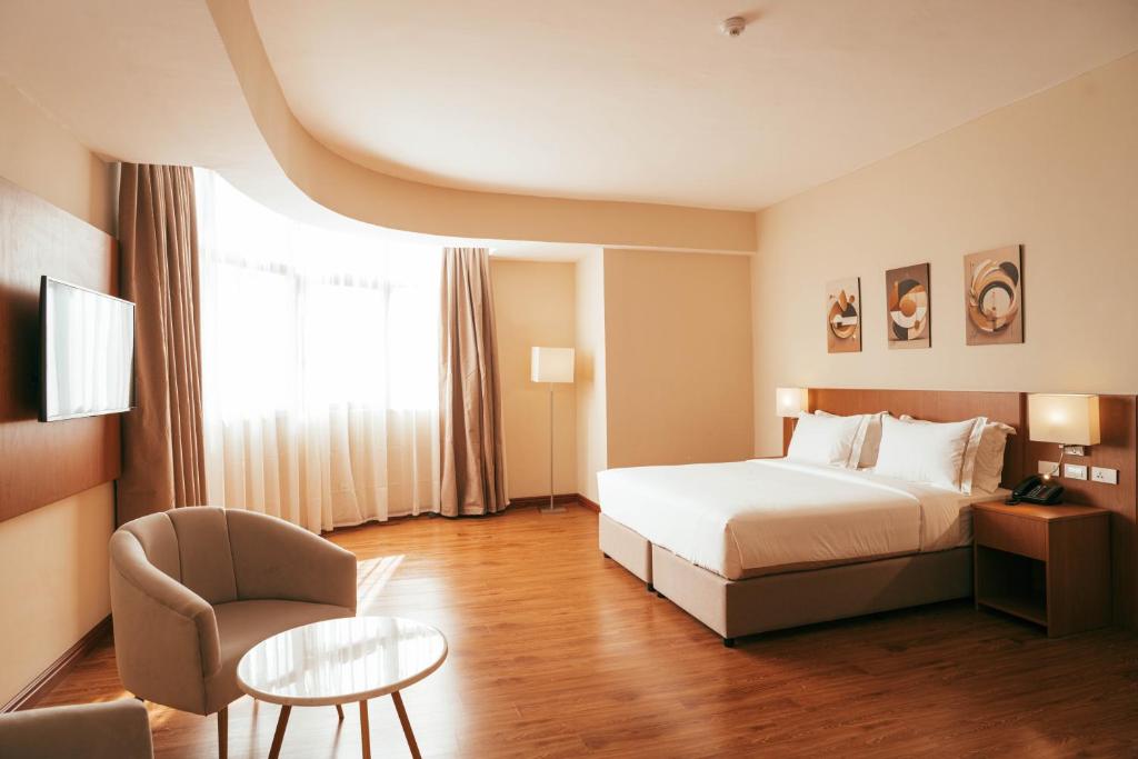 Pokój hotelowy z łóżkiem, krzesłem i stołem w obiekcie AYA Addis Hotel w Addis Abebie