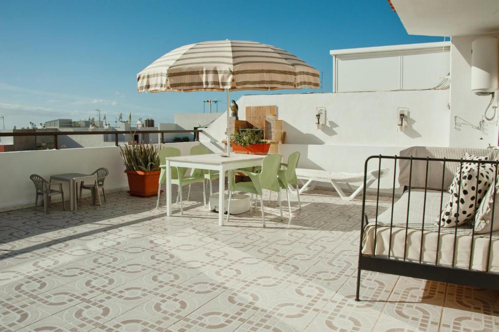 a patio with a table and an umbrella on a roof at Studio Ático with Terrace - Heart of Los Cristianos in Arona