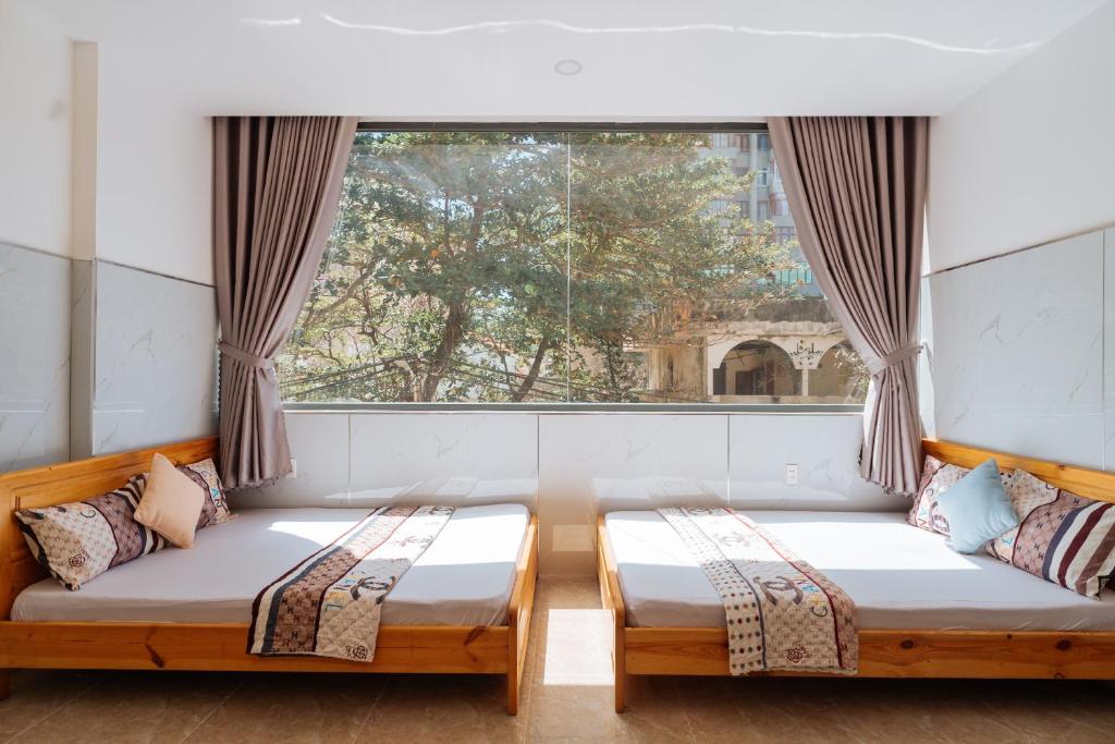 two beds in a room with a window at Quốc Thắng Hotel in Vung Tau