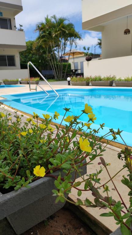 a swimming pool with flowers in front of a house at Pipa Céu Azul in Pipa