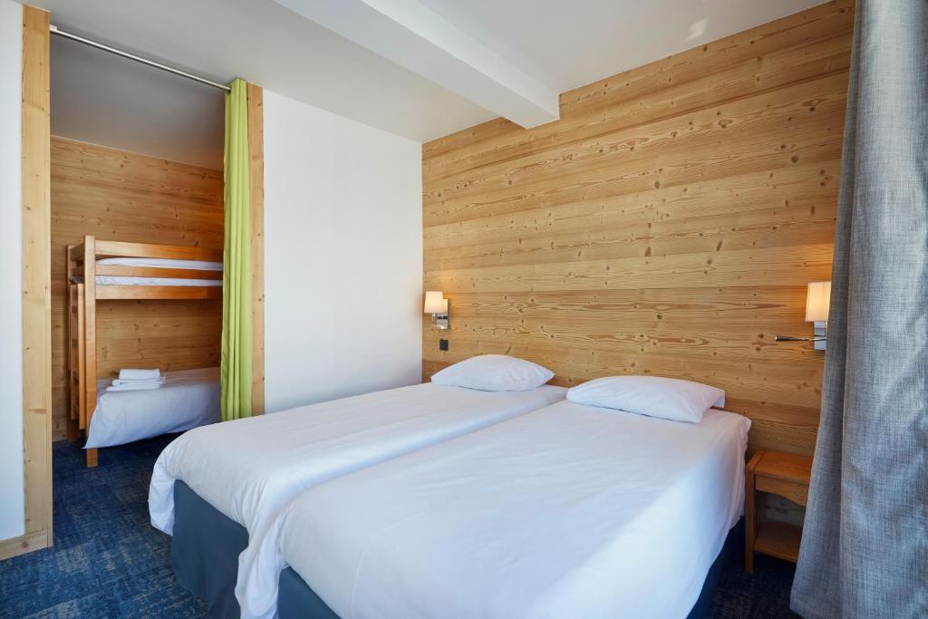 two beds in a room with wooden walls at Hôtel Eliova Le Chaix in L'Alpe-d'Huez