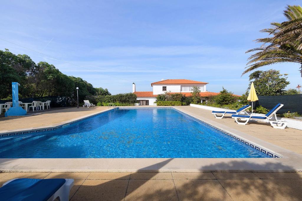 a pool with chairs and a house in the background at Alto da Praia Villa in Colares