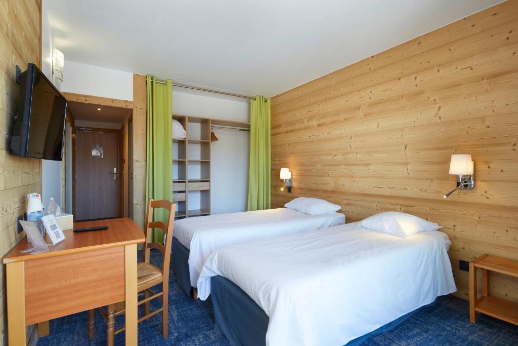 a hotel room with two beds and a desk and a desk at Hôtel Eliova Le Chaix in L'Alpe-d'Huez