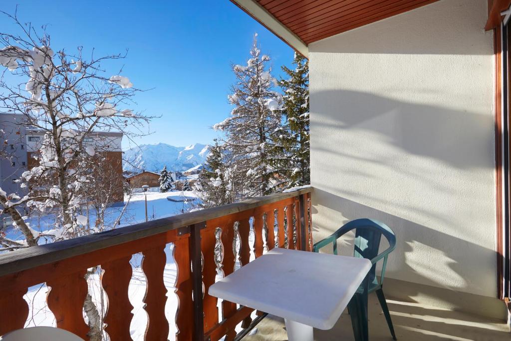 a balcony with a table and a view of snow covered trees at Hôtel Eliova Le Chaix in L'Alpe-d'Huez