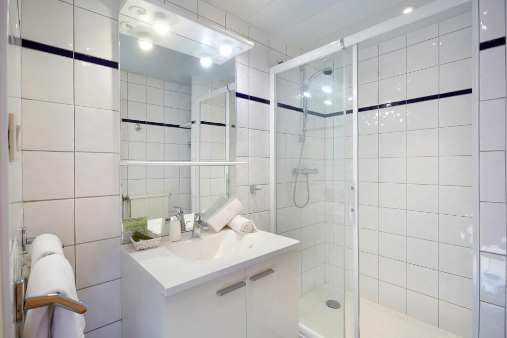 a white bathroom with a sink and a shower at Hôtel Eliova Le Chaix in L'Alpe-d'Huez