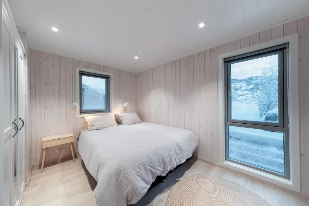 um quarto com uma cama e duas janelas em Vikran Seaside Lodge em Straumsjøen
