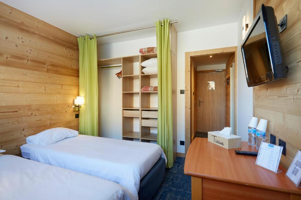 a hotel room with two beds and a television at Hôtel Eliova Le Chaix in L'Alpe-d'Huez