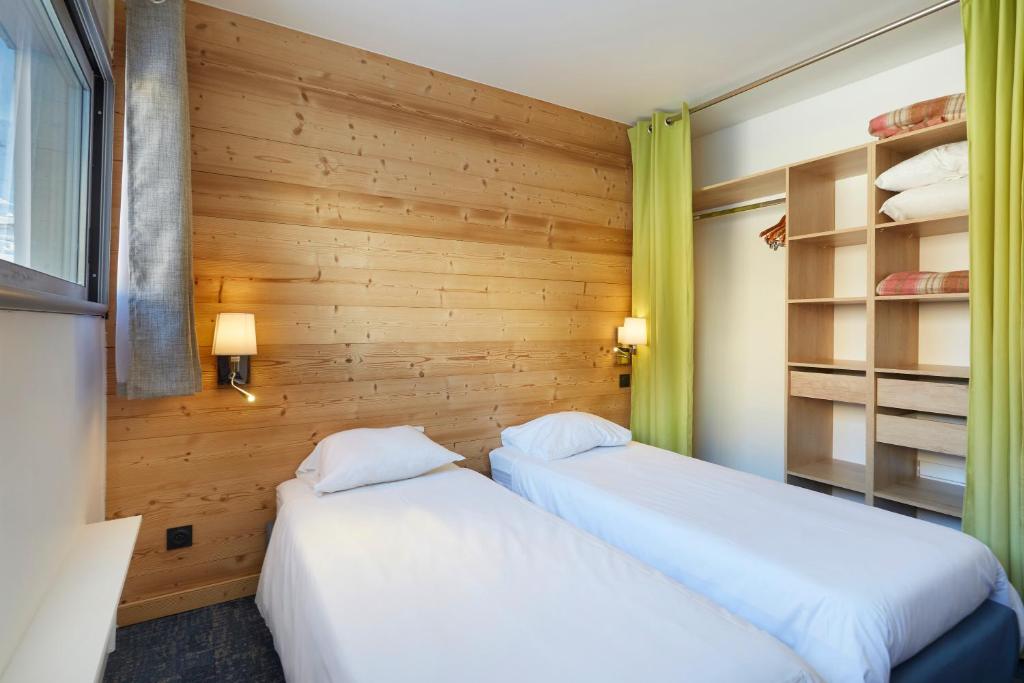 two beds sitting next to each other in a room at Hôtel Eliova Le Chaix in L'Alpe-d'Huez