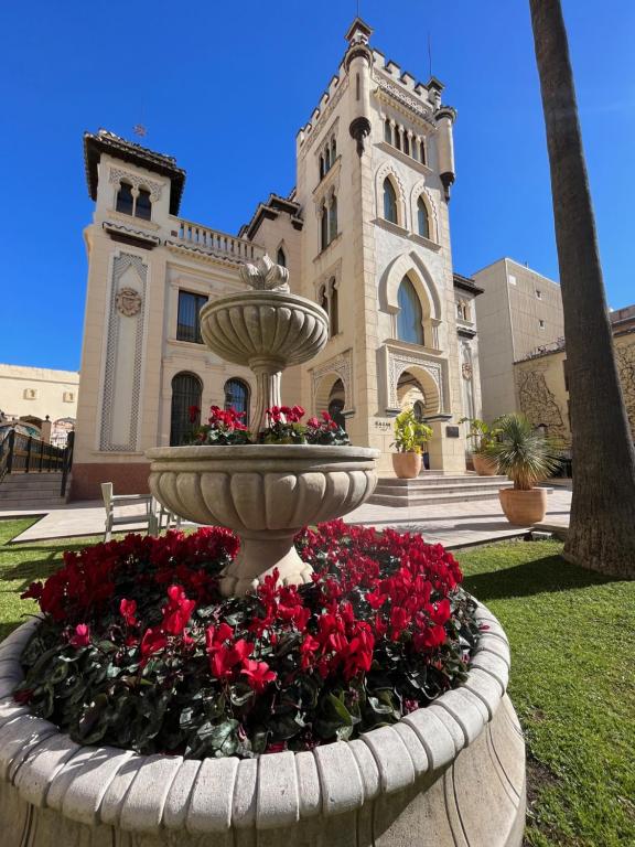 a fountain with red flowers in front of a building at Hotel Kazar in Ontinyent