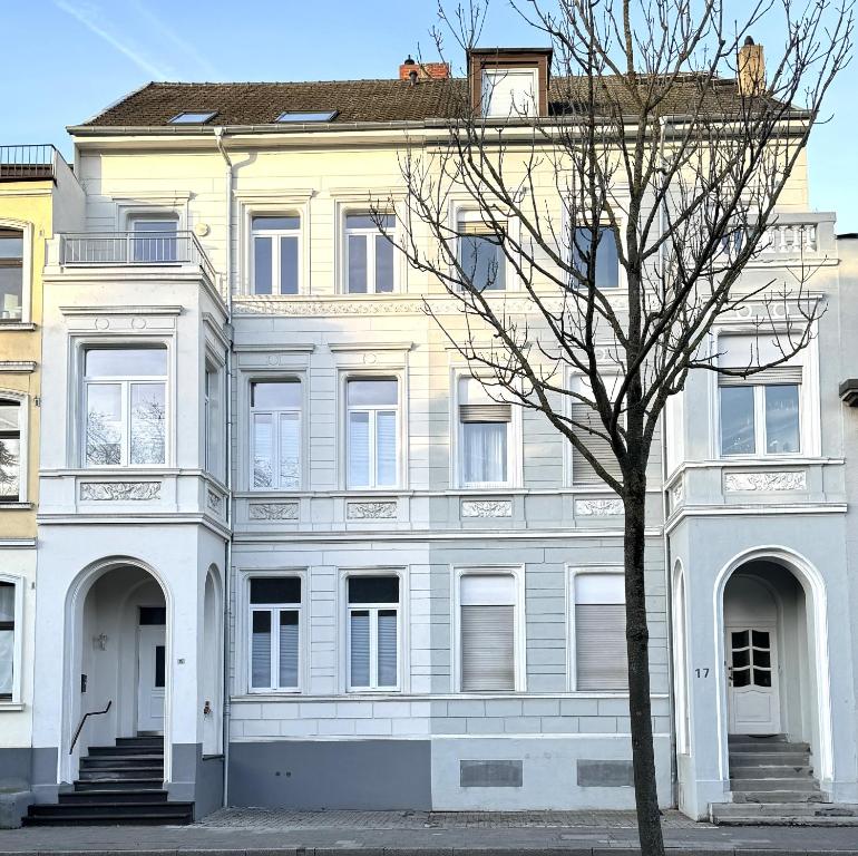 a white building with a tree in front of it at Der Schwan, Innenstadt, 2022 renoviert in Düren - Eifel