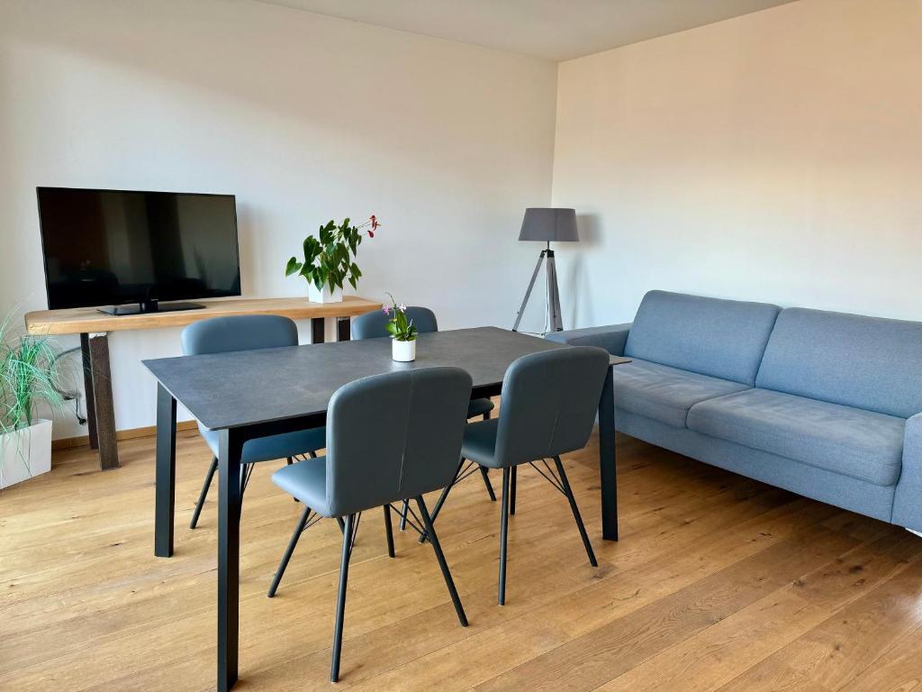 a living room with a table and a blue couch at Ferienwohnungen Preiss in Schenna