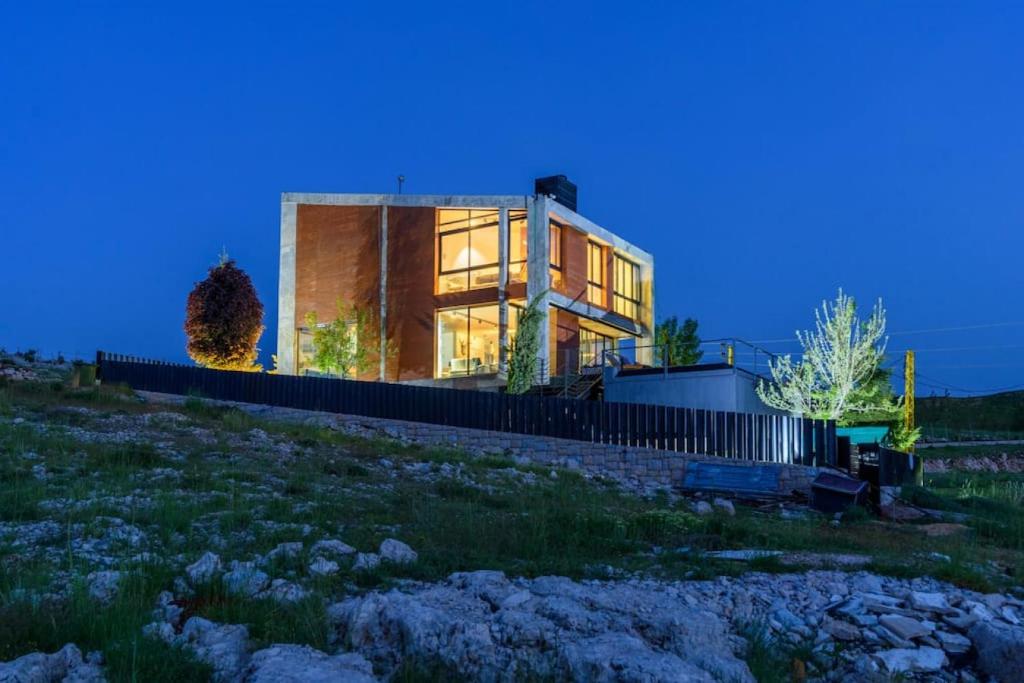 una casa seduta in cima a una collina di notte di Luxury Stay at Bakish Peaks Villa with pool 