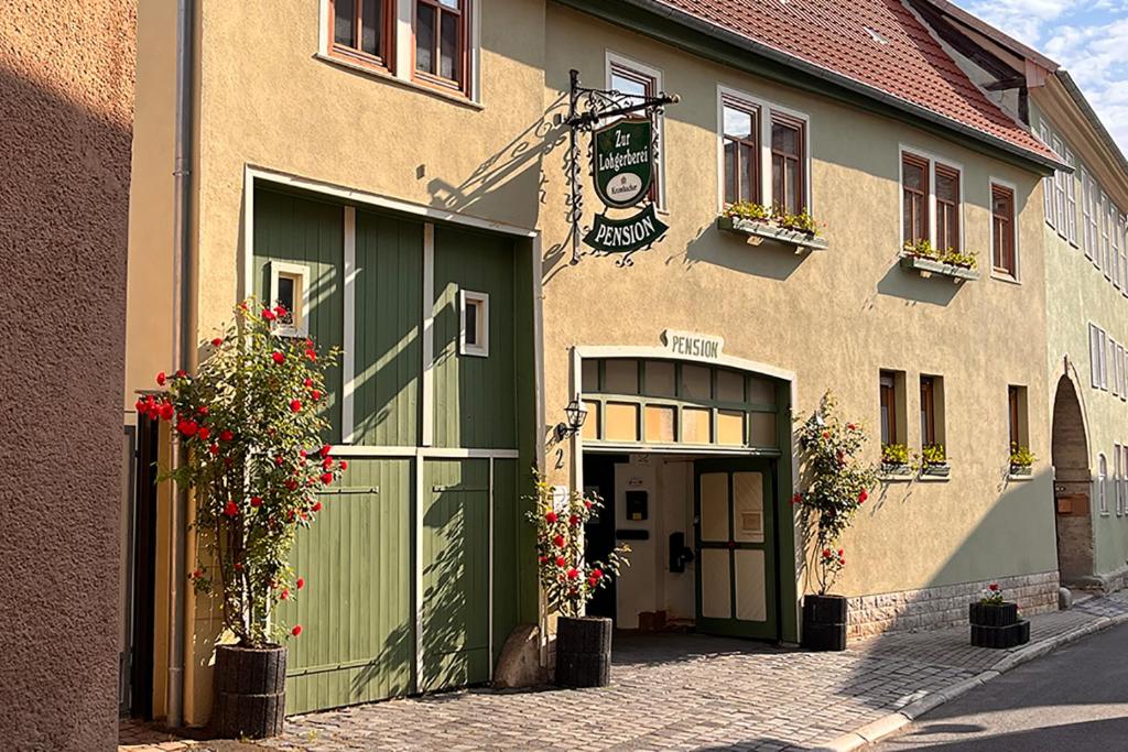 バート・ランゲンザルツァにあるPension "Zur Lohgerberei"の緑のドアと花が目の前に咲く建物