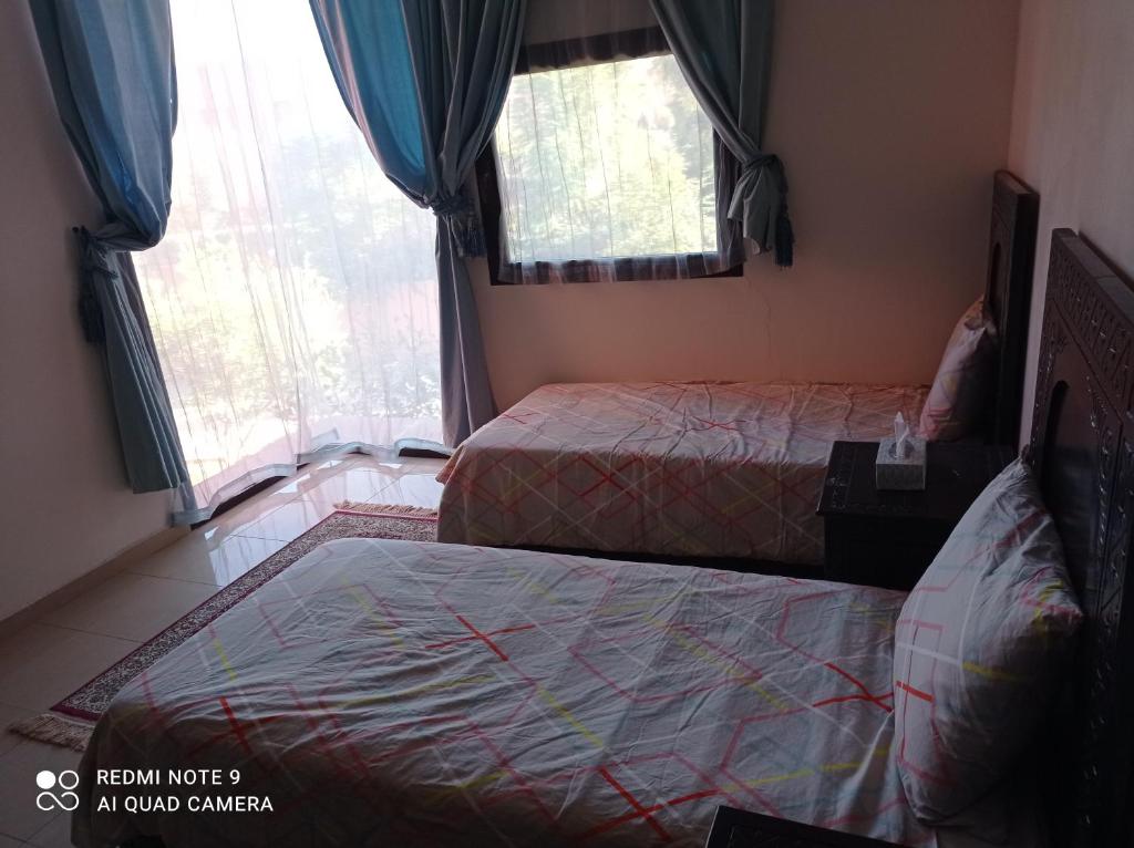 Appartement في مراكش: غرفة نوم بسريرين ونوافذ