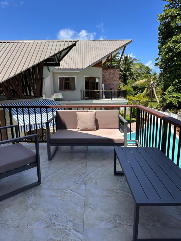 a patio with a couch and two benches on a deck at Villa Source D'Argent in La Digue