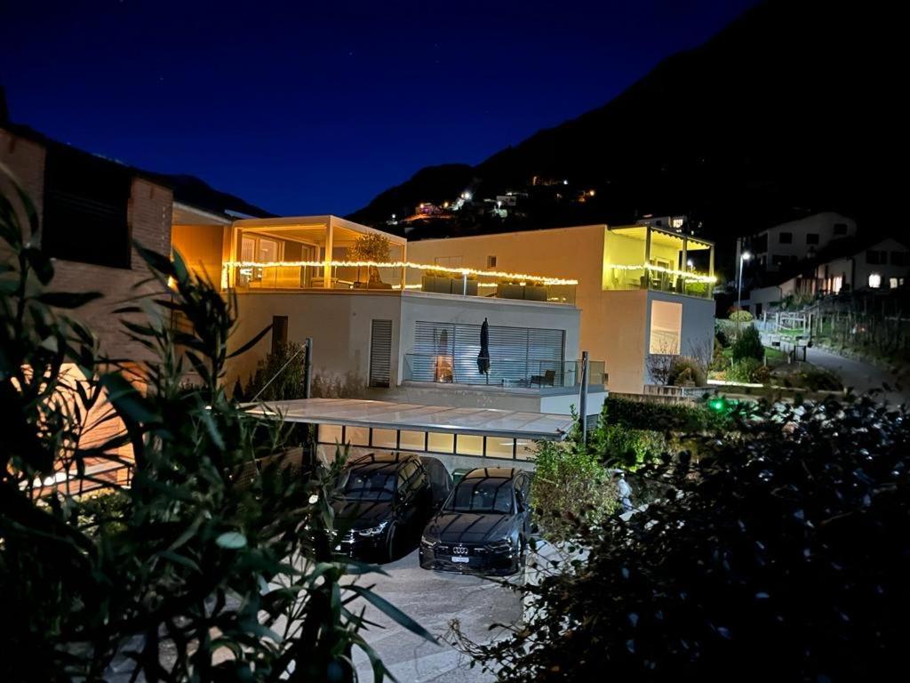dos autos estacionados frente a una casa por la noche en Violet-Sky Bellinzona, en Bellinzona