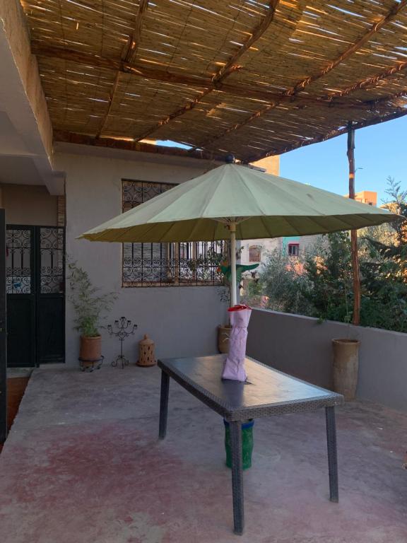 una mesa con una sombrilla verde en el patio en Maison vallée de l'Ourika en Marrakech
