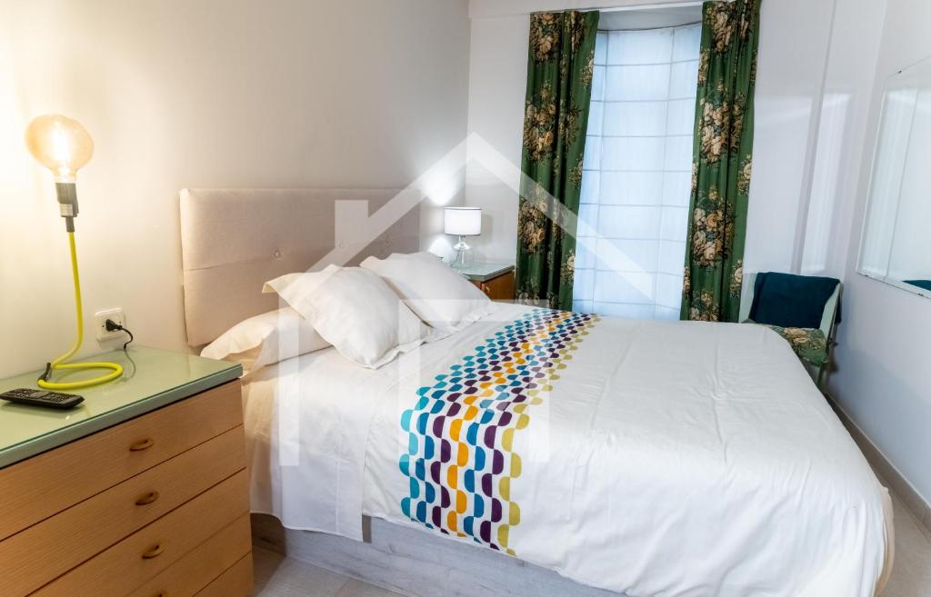 Un dormitorio con una cama blanca con una manta de colores. en Cimadevilla, en Oviedo