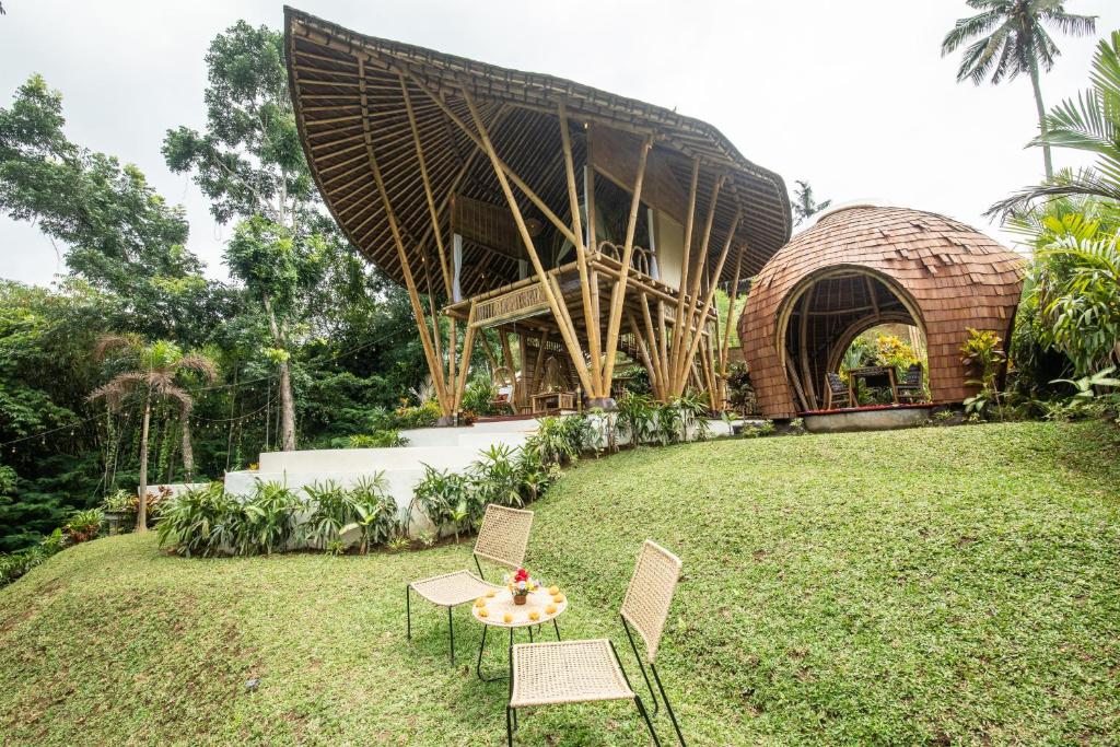 einen Tisch und Stühle auf dem Rasen vor einem Gebäude in der Unterkunft Magical Bamboo House with Breathtaking view in Selat