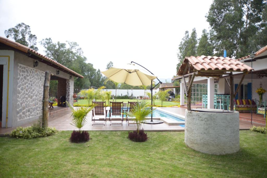 a patio with a table and an umbrella in a yard at Casa de Campo Solar Tere in Cochabamba