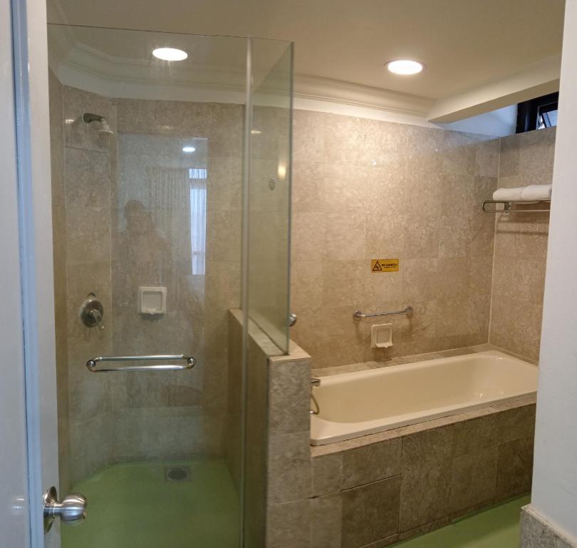 a bathroom with a shower with a tub and a bath tub at CITY APARTMENT at TIMES SQUARE in Kuala Lumpur