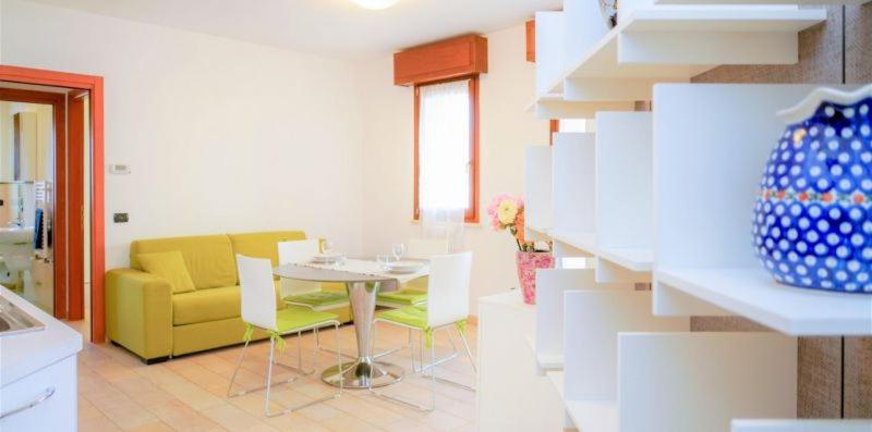 ein Wohnzimmer mit einem Tisch und einem gelben Sofa in der Unterkunft Vis Bella Apartment in Rimini