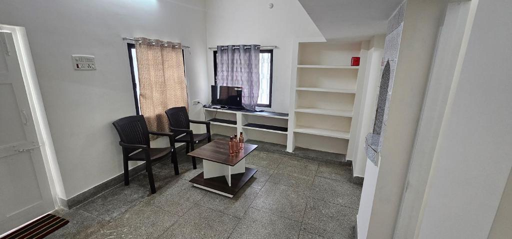 a small room with a desk and chairs and a table at SAIBALA HOMESTAY - AC 1 BHK NEAR AlRPORT in Chennai