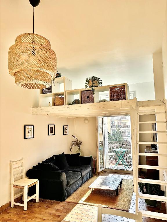 - un salon avec un canapé noir et un lustre dans l'établissement Appartement cosy au cœur de Sète, à Sète