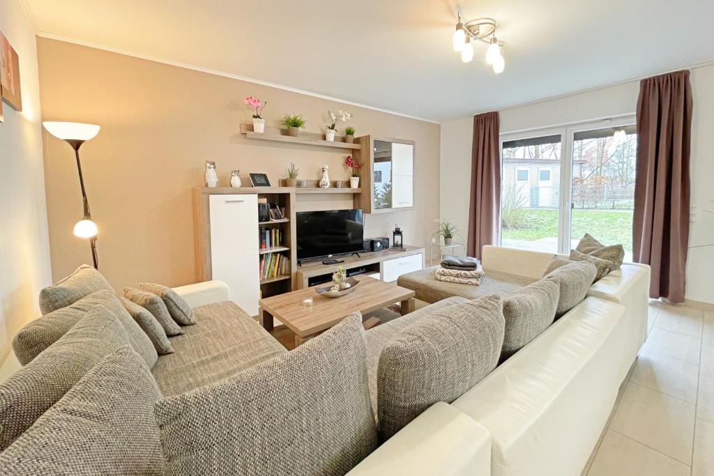 a living room with a white couch and a table at Strandstrasse 21 Ferienwohnung Möwennest in Kölpinsee