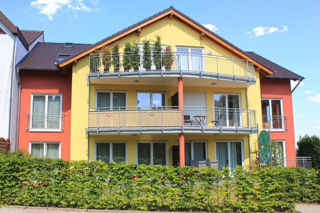 ein gelbes und rotes Haus mit einem Balkon in der Unterkunft Ferien im Maigen in Tünsdorf