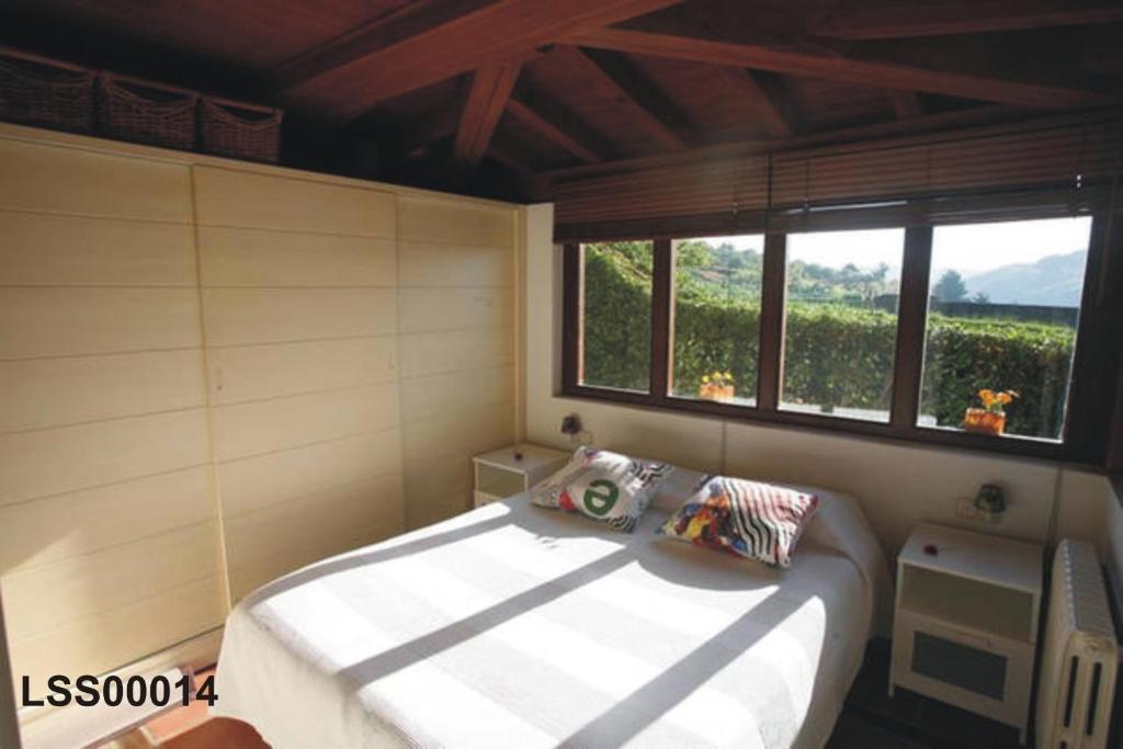 ein Schlafzimmer mit einem Bett in einem Zimmer mit einem Fenster in der Unterkunft 2 HABIT, SALA, TERRAZA, JARDIN, PARKING GRATiS in Zumaia