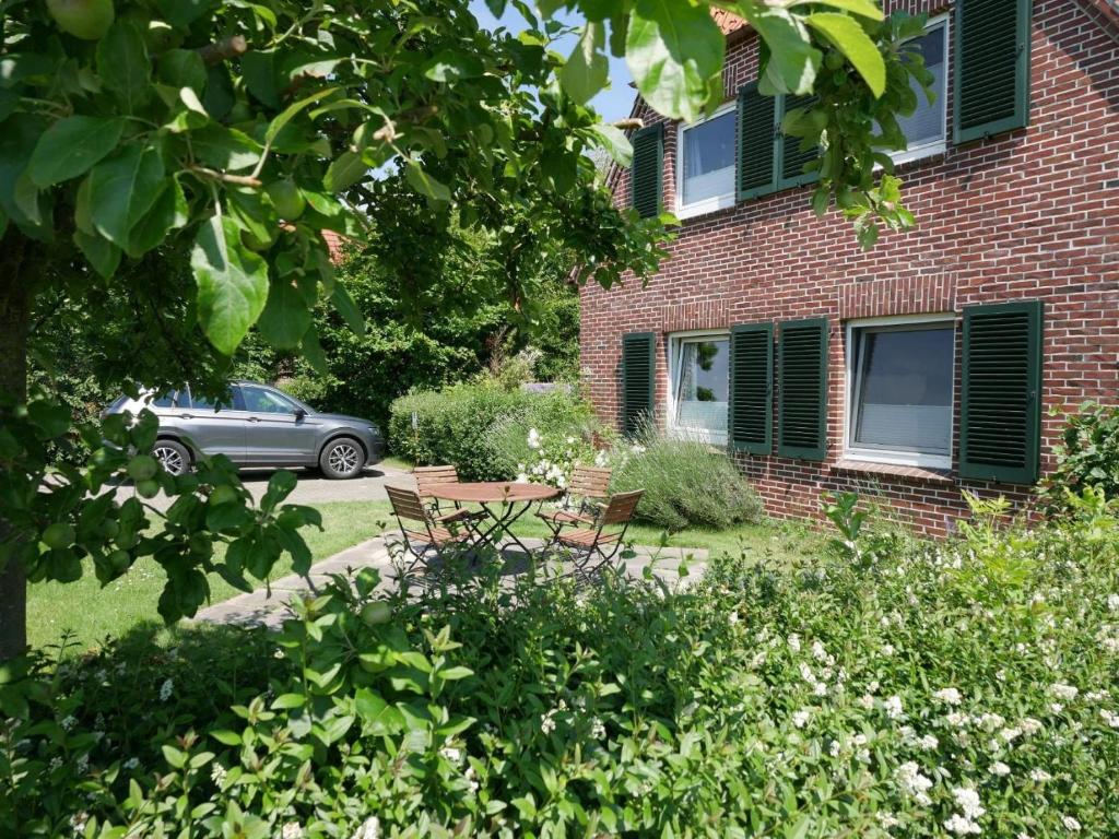 a garden with a table and chairs in front of a brick building at Nordapart Anne Bessrich in Butjadingen