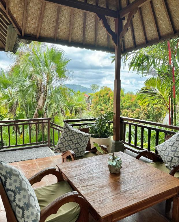 un portico con tavolo e sedie in legno sul balcone di Sawah Indah Villa a Sidemen