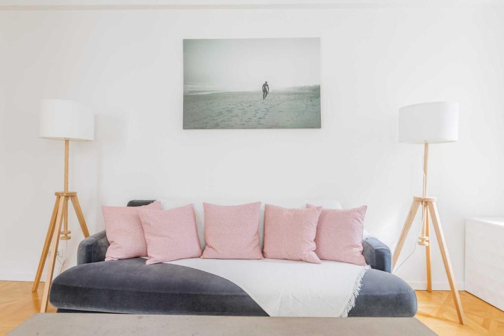 a living room with a couch with pink pillows at Lovely flat in the 16th arrondissement not far from the Trocadéro in Paris