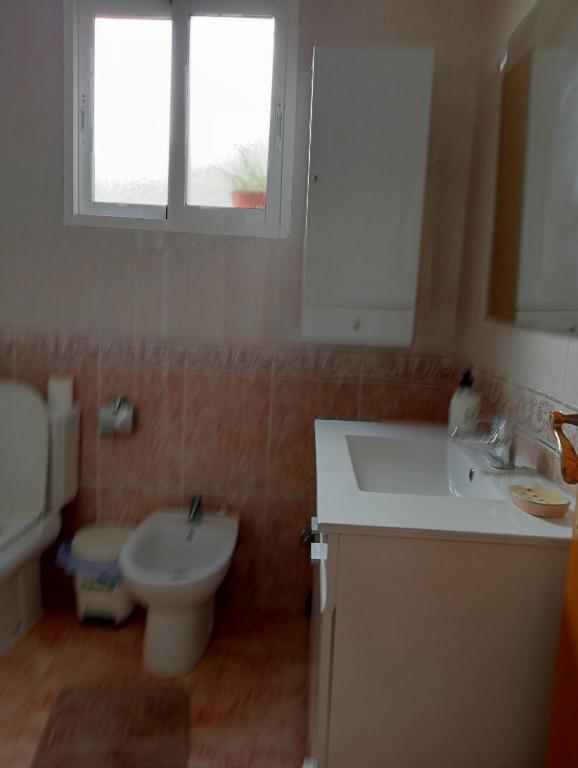 a bathroom with a sink and a toilet and a window at Habitaciónes Privadas Cartagena Murcia in Cartagena