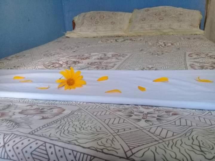Una cama blanca con una flor amarilla. en Thurusewana guest, en Anuradhapura