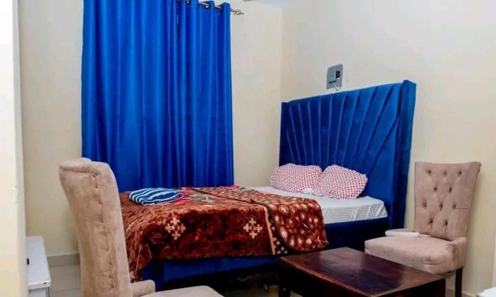 a room with a bed with blue curtains and a table at Ziggon villa mtwapa in Mombasa