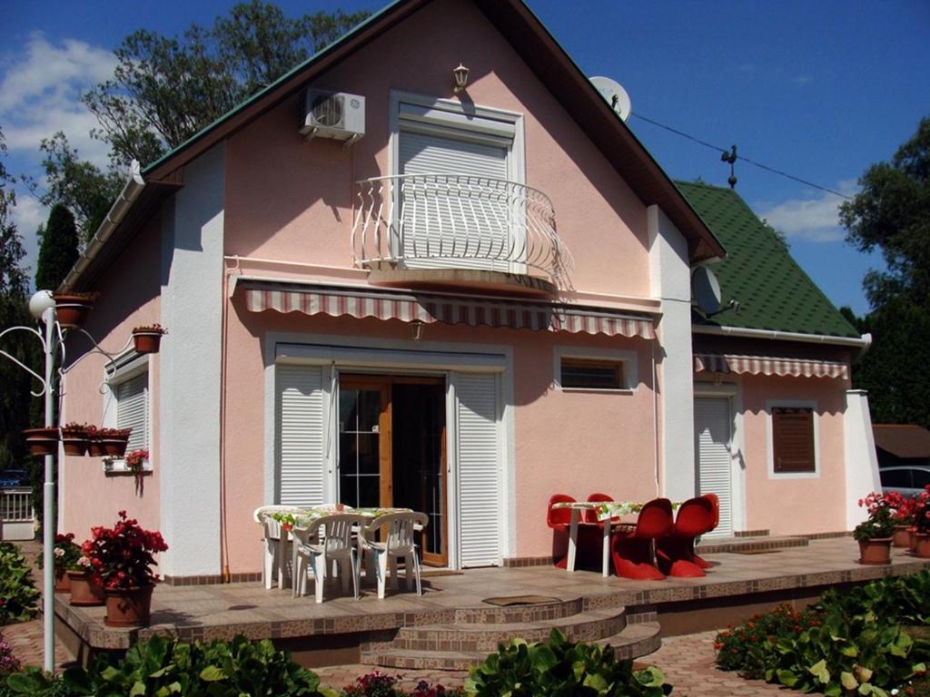 ein rosafarbenes Haus mit Tischen und Stühlen davor in der Unterkunft Nyaraló Balatonmáriafürdő in Balatonmáriafürdő
