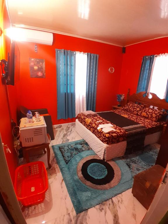 a bedroom with red walls and a bed and a rug at Mandy's Homestay in Couva