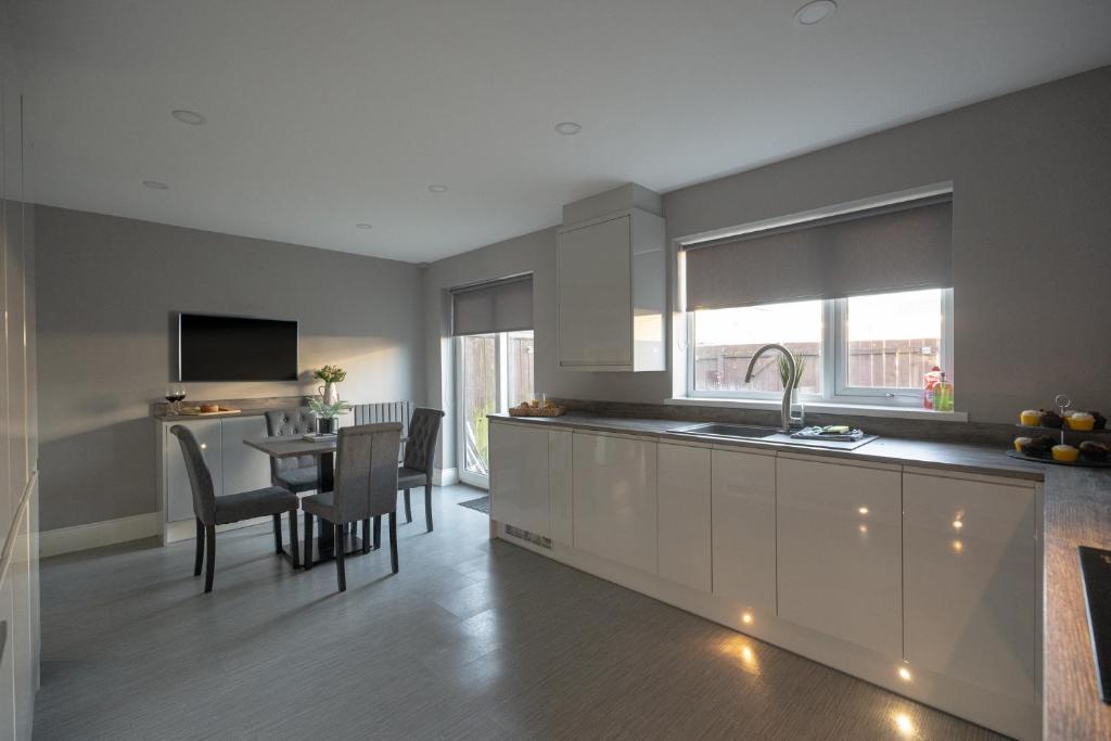 a kitchen with a sink and a table with chairs at Pine House By Horizon Stays in Hartlepool