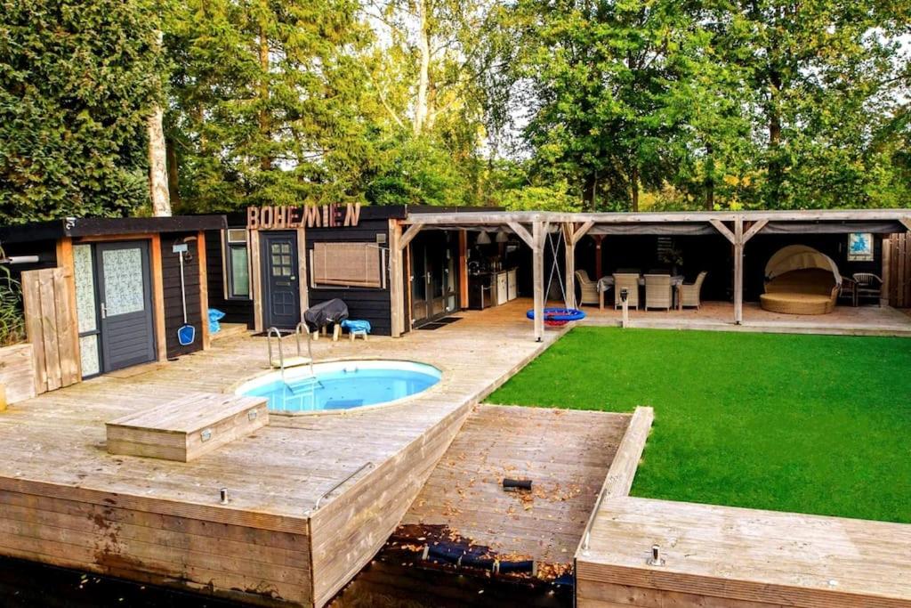 a house with a pool on a wooden deck at Bohemian Island incl boat supboards and pool 5 minutes by boat from parking to the bohemien in Loosdrecht