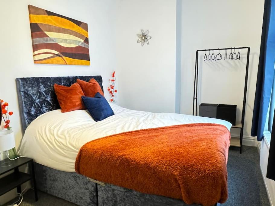 um quarto com uma cama com almofadas laranja e azul em Cosy home in Barnsley centre em Barnsley