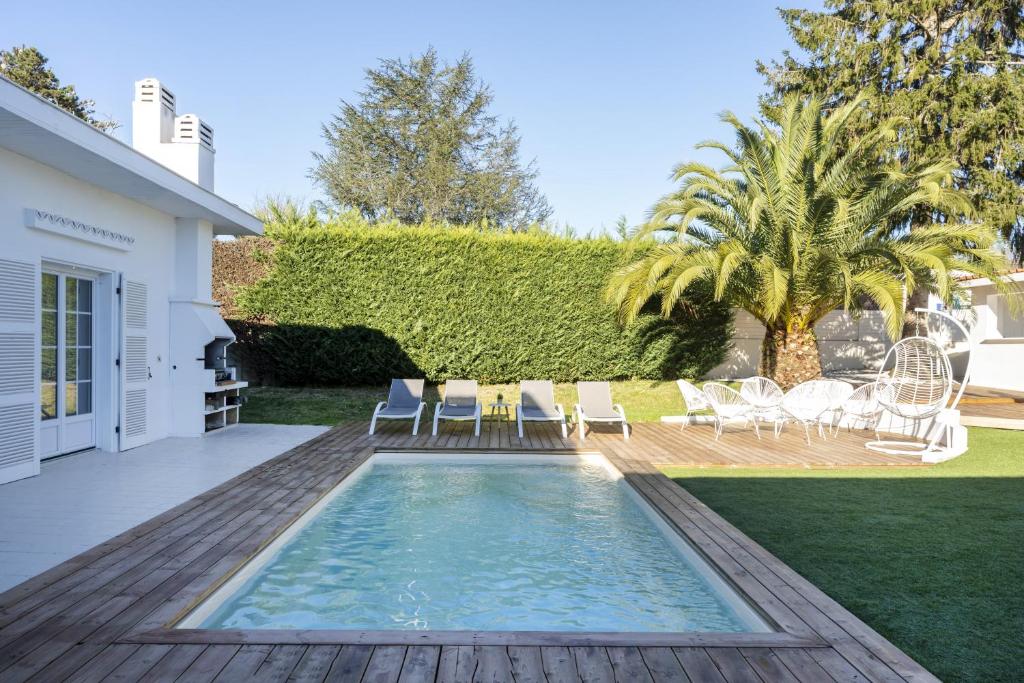 a backyard with a swimming pool and a patio with chairs at Villa standing Biarritz in Biarritz