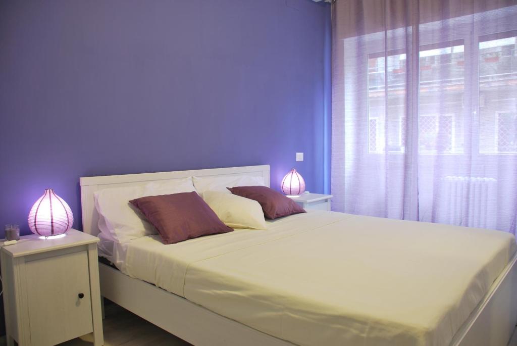 1 dormitorio con 1 cama con paredes moradas y 2 lámparas en Victoria Apartment, en Roma