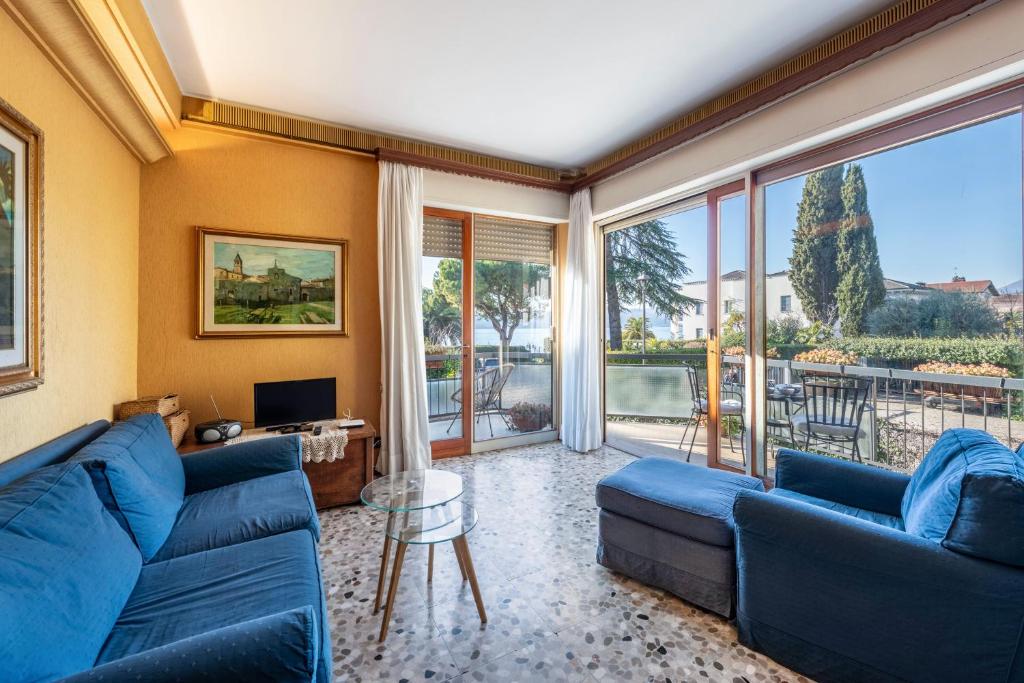 sala de estar con sofás azules y ventana grande en Spiaggia d'oro Apartment Lake View, en Montecucco